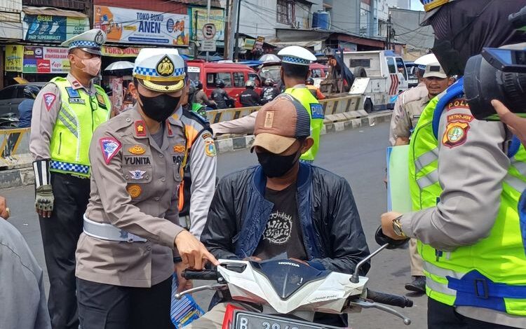 Kasat Lantas Polres Metro Jakarta Selatan Kompol Yunita Rungkat saat mengecek surat-surat berkendara seorang pengendara motor yang tak menggunakan helm di persimpangan Pasar Minggu, Jakarta Selatan.